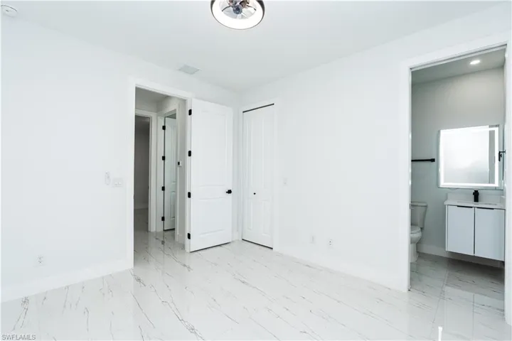 Unfurnished bedroom with light marble finish flooring, ensuite bathroom, and a closet