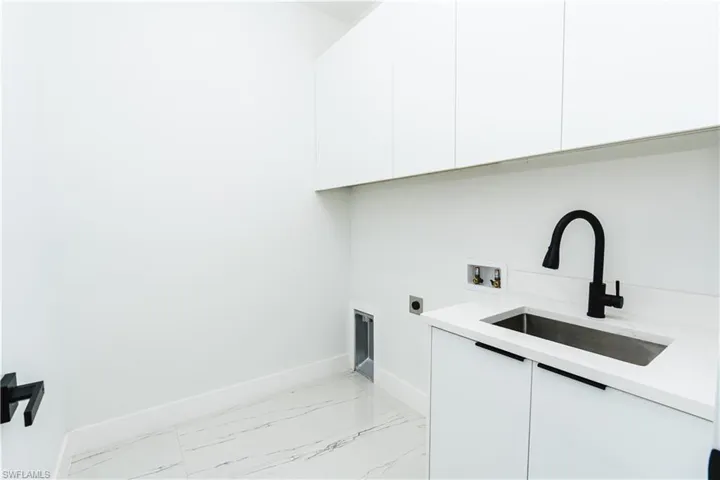 Washroom featuring cabinet space, hookup for an electric dryer, light marble finish flooring, and washer hookup