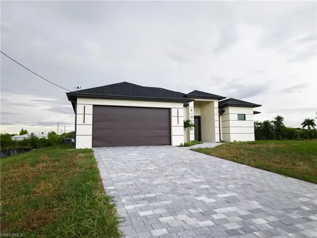 View of front of house featuring decorative driveway, stucco siding, an attached garage, and a front lawn
