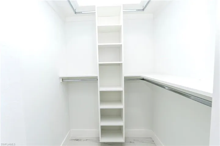 Walk in closet featuring light marble finish floors