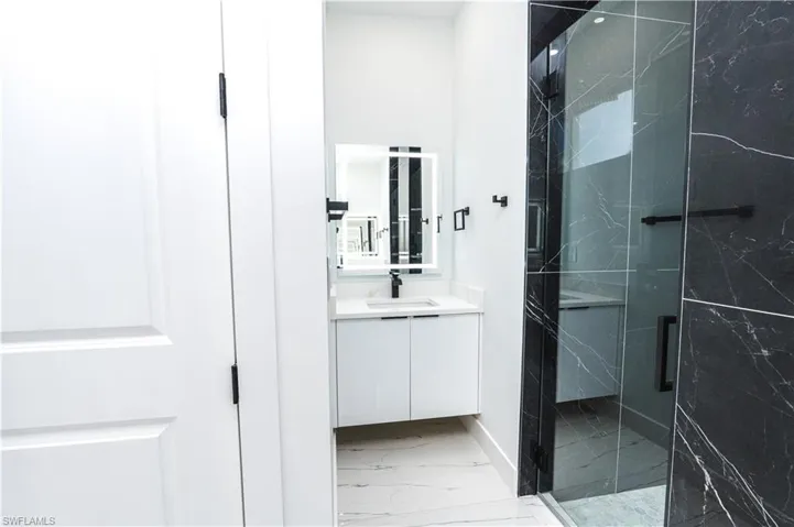 Bathroom with vanity, a marble finish shower, and light marble finish floors