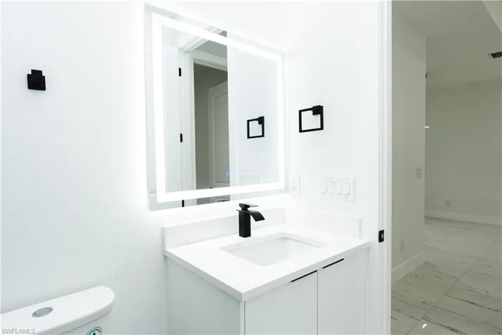 Half bath featuring vanity and light marble finish flooring