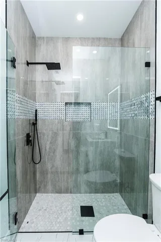 Full bath featuring toilet and tiled shower