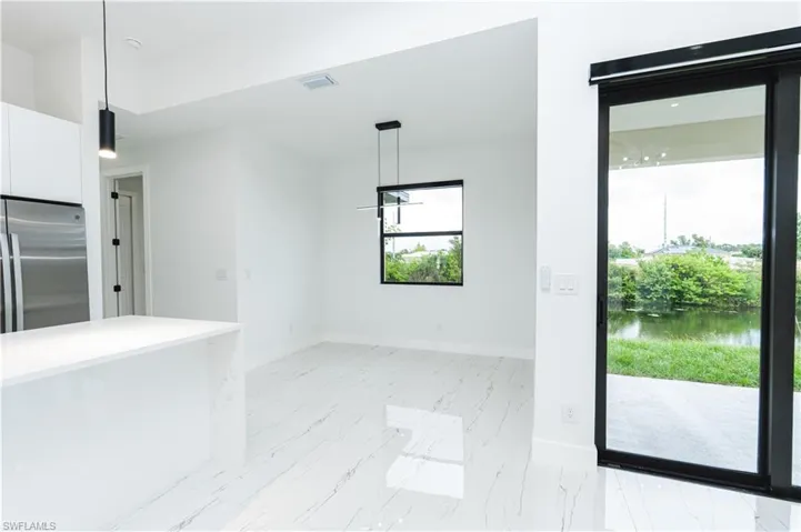 Kitchen with appliances with stainless steel finishes, tasteful backsplash, a kitchen island with sink, light stone counters, and decorative light fixtures