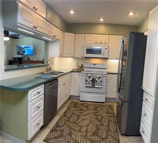 Kitchen featuring white appliances, white cabinetry, recessed lighting, a peninsula, and ceiling fan