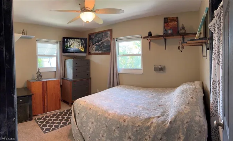 Carpeted bedroom featuring multiple windows and ceiling fan