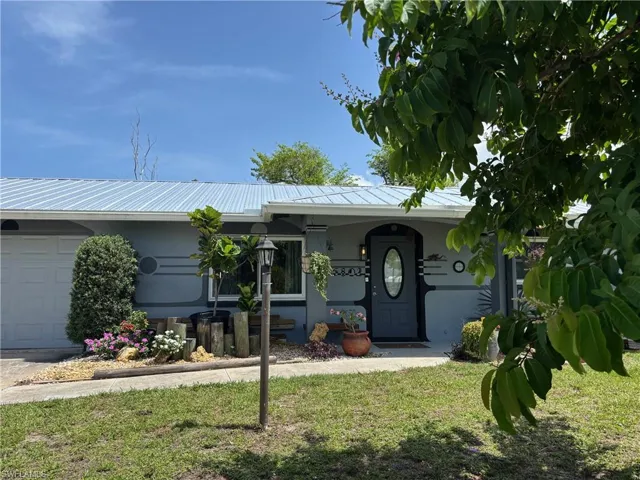 Ranch-style home featuring a metal roof, a garage, and a front yard
