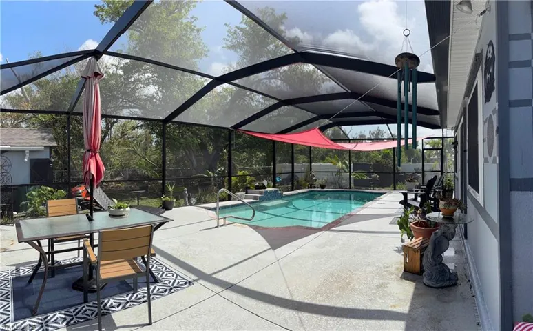 View of swimming pool with a patio area, outdoor dining area, and glass enclosure