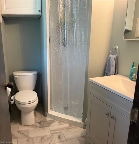 Bathroom with marble look tile flooring, vanity, and a shower stall