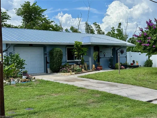 Single story home featuring an attached garage, driveway, stucco siding, and a metal roof