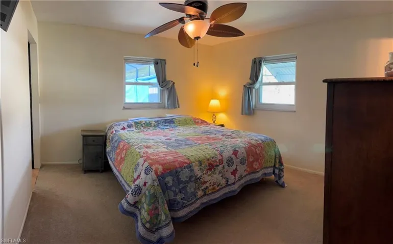 Bedroom featuring multiple windows, carpet, and a ceiling fan