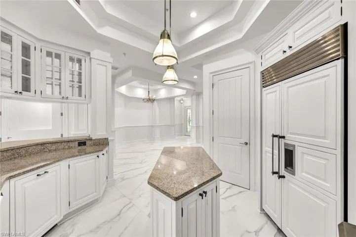 Kitchen featuring light stone countertops, white cabinetry, pendant lighting, and paneled sub-zero refrigerator