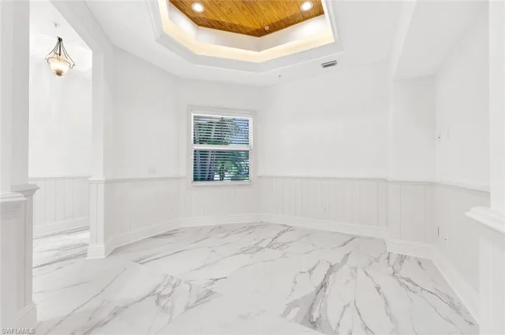 Front sitting room with a tray ceiling, light marble finish floors, recessed lighting, wainscoting, and wooden ceiling