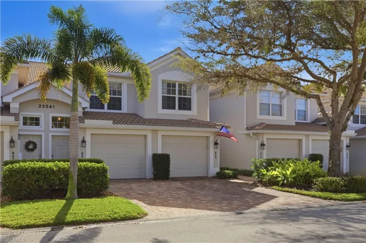 View of front facade featuring a garage, decorative driveway, a tile roof, and stucco siding