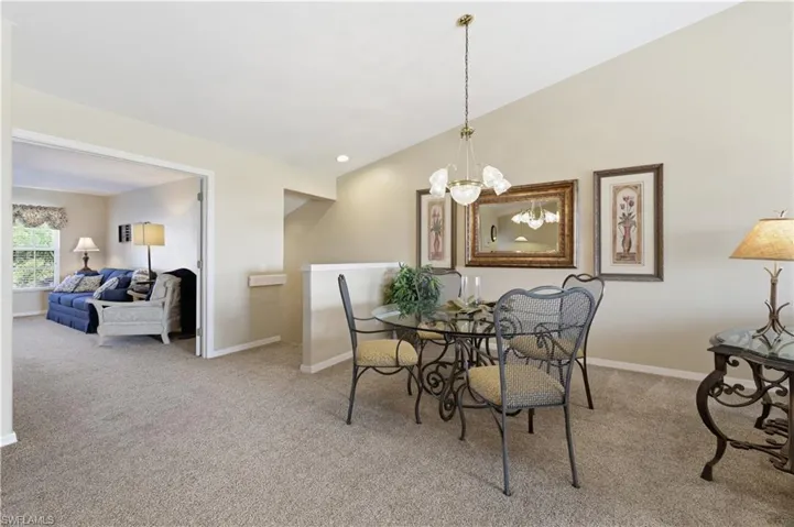 Dining room featuring light colored carpet, a chandelier, and vaulted ceiling
