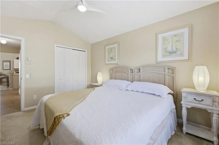 Bedroom with lofted ceiling, light carpet, a closet, and a ceiling fan