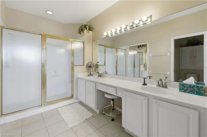 Full bath featuring double vanity, a shower stall, and light tile patterned floors