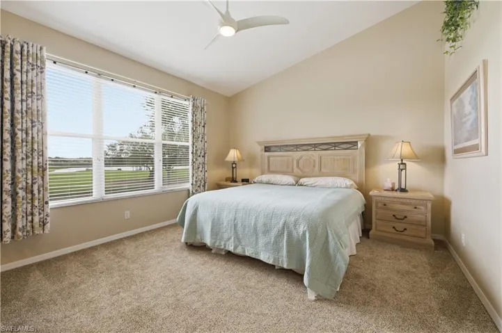 Bedroom with lofted ceiling, light carpet, and a ceiling fan