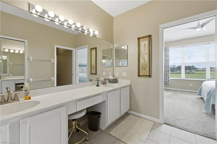 Bathroom featuring connected bathroom, double vanity, light colored carpet, light tile patterned floors, and ceiling fan