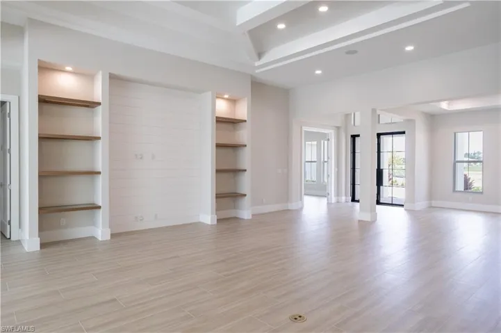 Unfurnished living room featuring recessed lighting, built in features, light wood-type flooring, and beamed ceiling