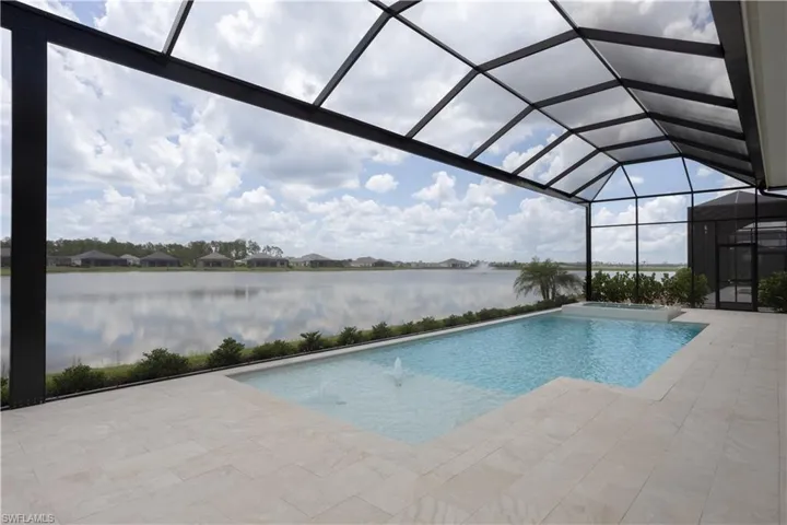 View of pool with a water view, a patio area, glass enclosure, a pool with connected hot tub, and a residential view