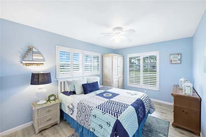 Bedroom with light hardwood / wood-style floors, multiple windows, and ceiling fan