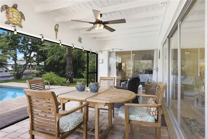 Sunroom / solarium featuring beamed ceiling, wood ceiling, and ceiling fan