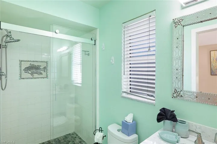 Bathroom featuring a shower with door, sink, and toilet