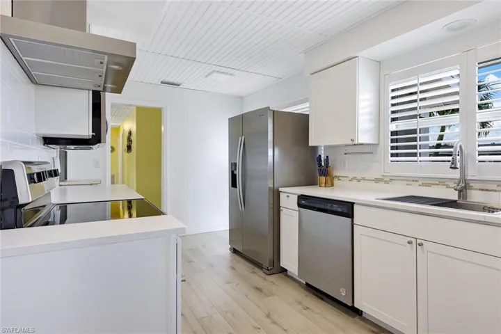 Kitchen featuring light hardwood / wood-style floors, tasteful backsplash, sink, white cabinets, and appliances with stainless steel finishes