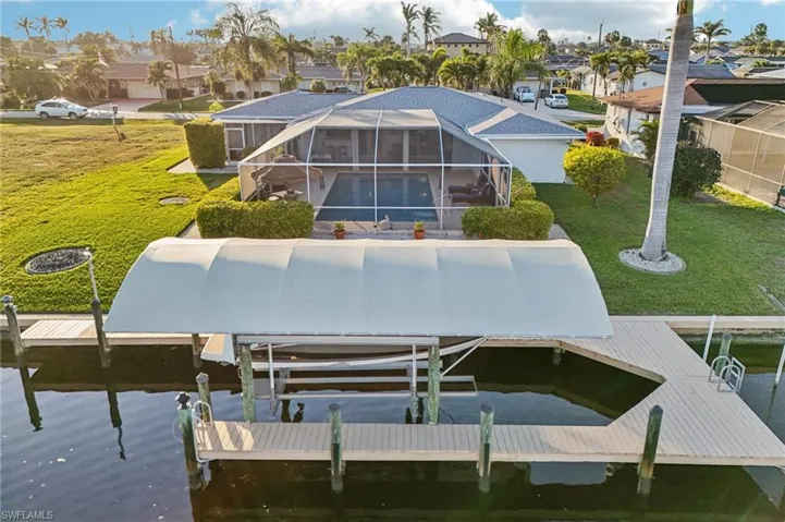 View of dock with a water view, a yard, and a lanai