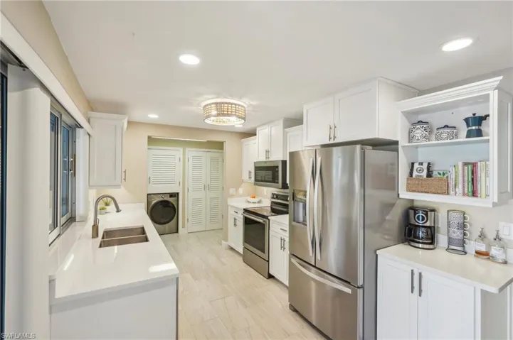Kitchen featuring sink, washer / clothes dryer, white cabinets, and appliances with stainless steel finishes