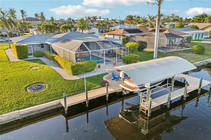 Dock area with a water view, a yard, and glass enclosure