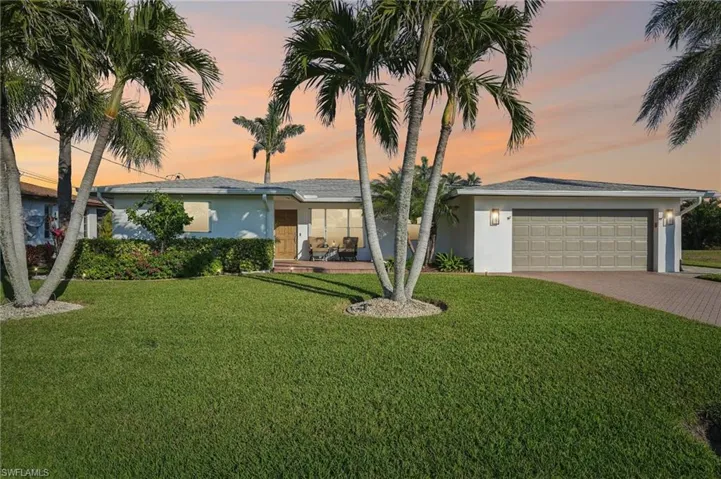 Ranch-style home featuring a garage and a lawn