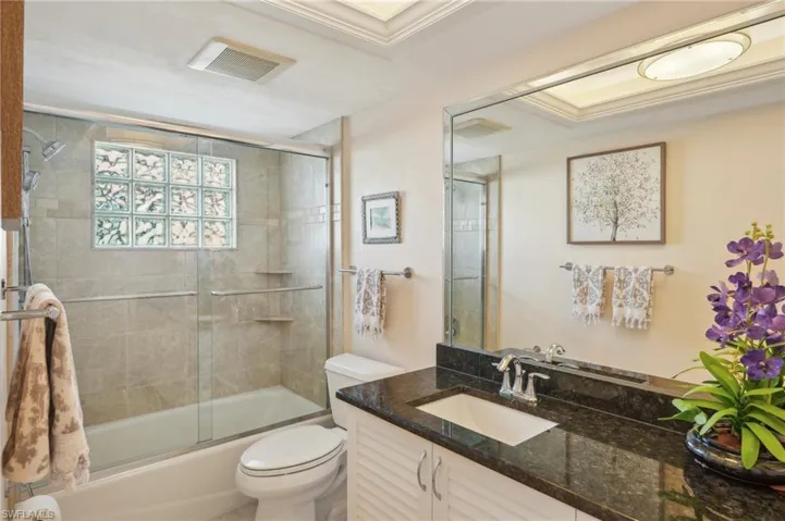 Full bathroom with toilet, vanity, and bath / shower combo with glass door