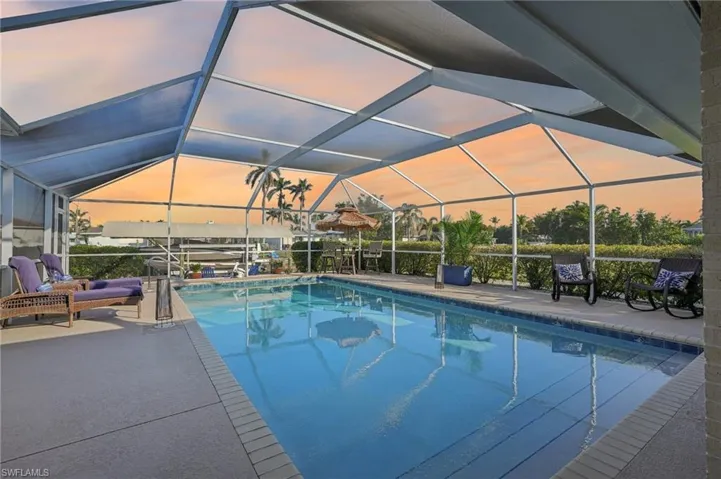 Pool at dusk with a lanai and a patio area