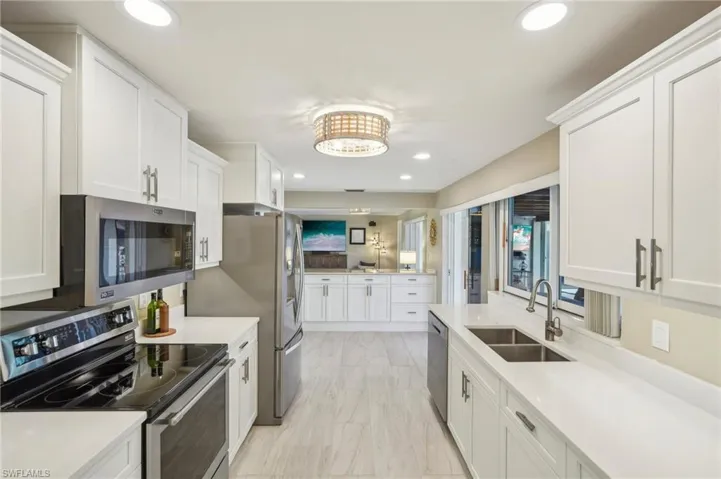 Kitchen with appliances with stainless steel finishes, sink, and white cabinets