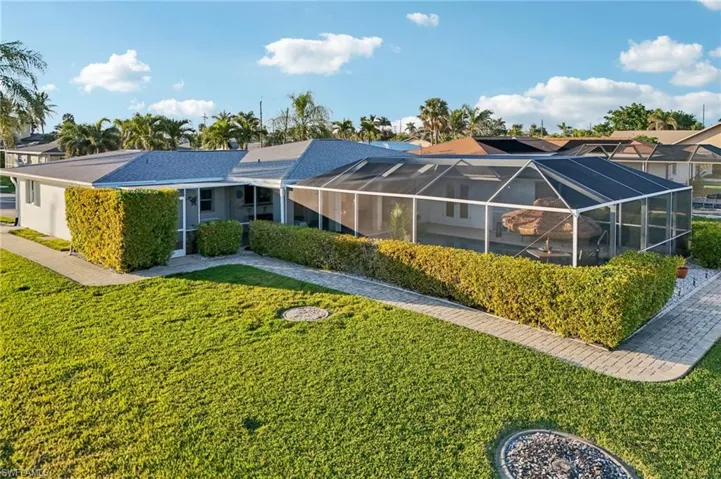 Rear view of property with a lanai and a lawn