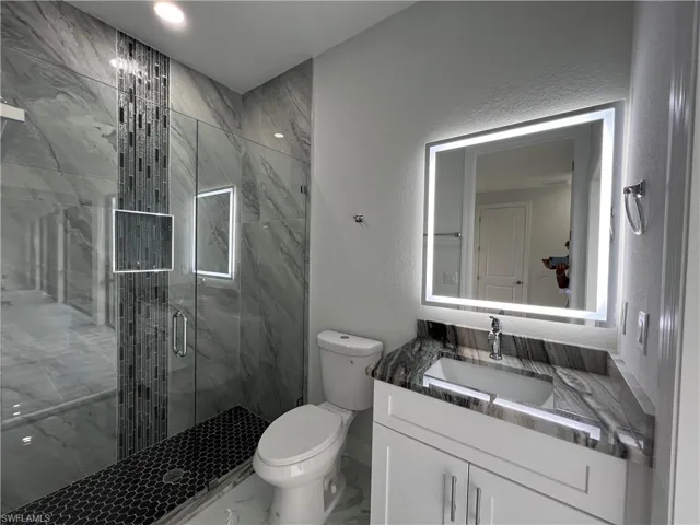 Bathroom 3 featuring a textured wall, a marble finish shower, vanity, and marble finish floors