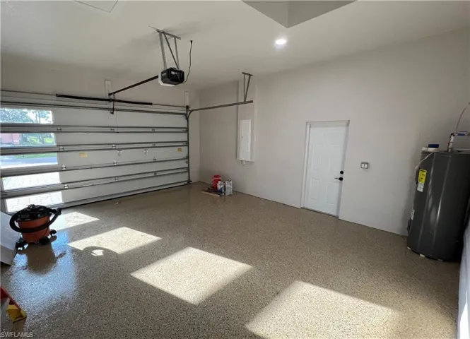 Garage featuring electric water heater, recessed lighting, electric panel, and a garage door opener