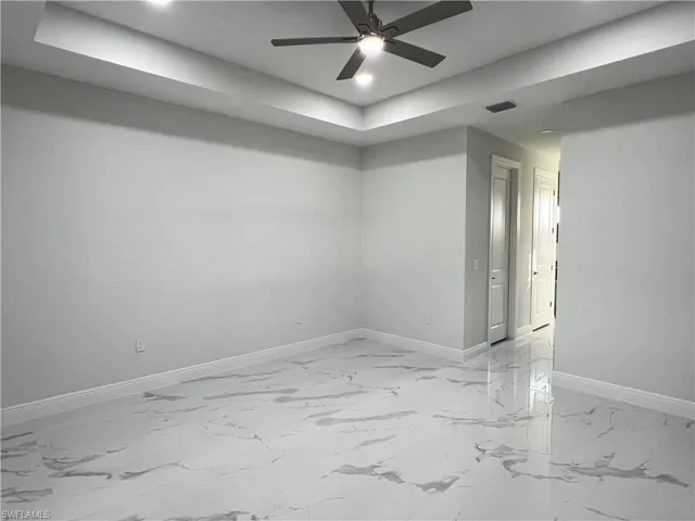 Master bedroom featuring a raised ceiling, light marble finish flooring, ceiling fan, and recessed lighting
