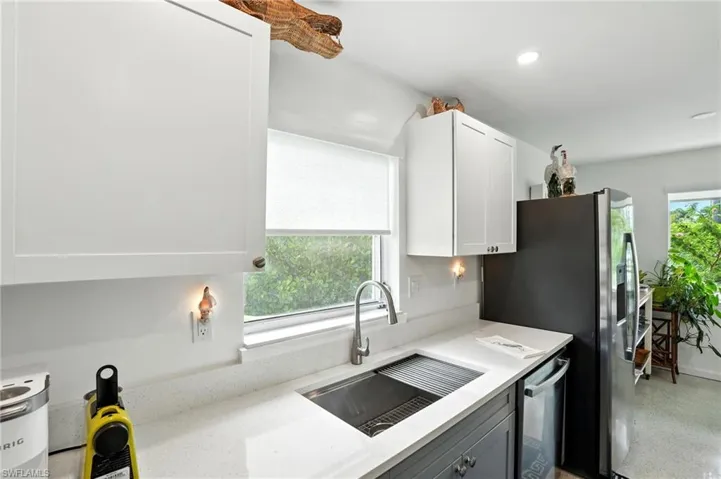 Kitchen featuring plenty of natural light, light stone countertops, dishwasher, recessed lighting, and white cabinetry
