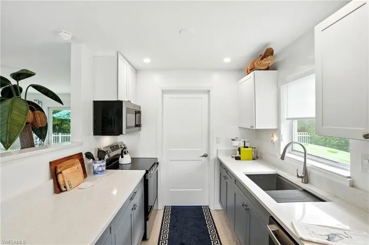 Kitchen with appliances with stainless steel finishes, light stone counters, white cabinets, recessed lighting, and gray cabinetry