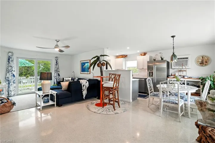 Living area featuring dark aggregate flooring, ceiling fan, recessed lighting, and a wall mounted air conditioner