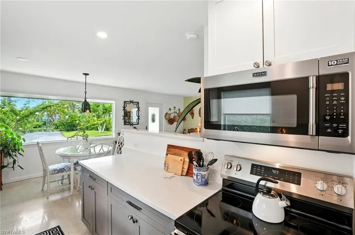 Kitchen featuring appliances with stainless steel finishes, hanging light fixtures, recessed lighting, light stone countertops, and gray cabinetry