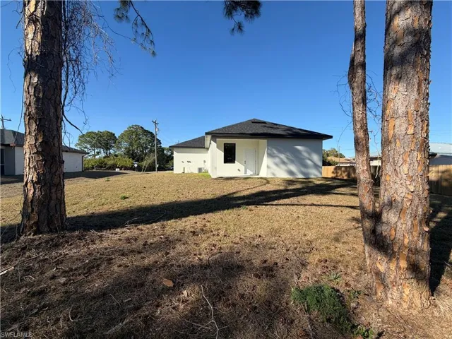 Back of property featuring a shingled roof and a yard