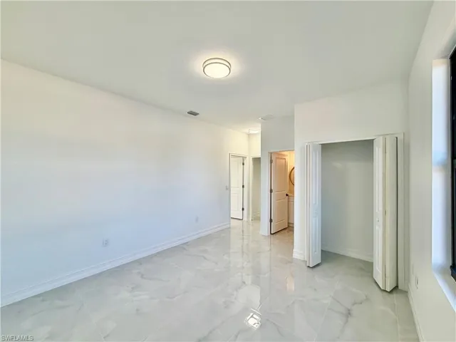 Unfurnished bedroom featuring a closet and light marble finish floors
