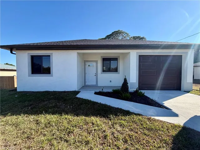 View of front facade featuring an attached garage, concrete driveway, stucco siding, and roof with shingles