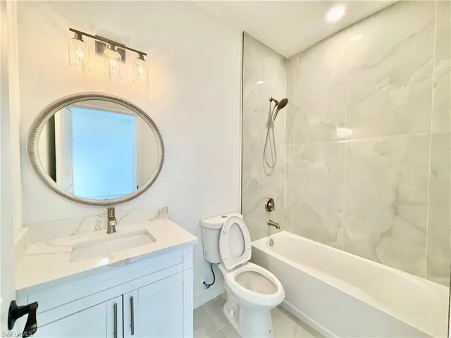Bathroom with vanity, shower / bath combination, and light tile patterned flooring