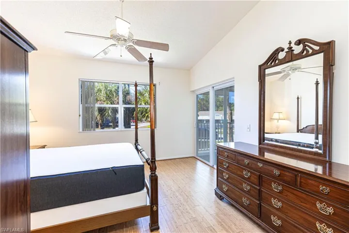 Primary bedroom featuring light wood-style flooring, ceiling fan, multiple windows, access to exterior & lofted ceiling.