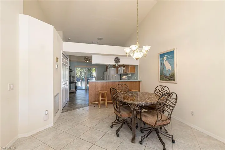 Dining area featuring chandelier, light tile patterned flooring & high vaulted ceiling.